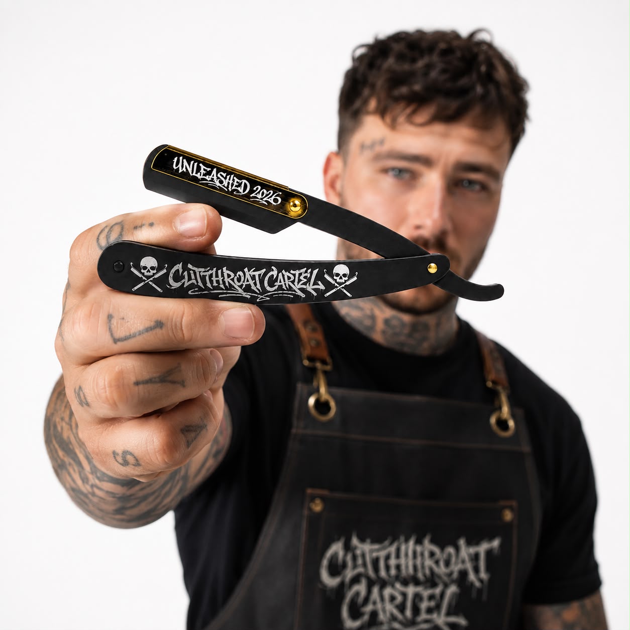 A barber holding the open Cutthroat Cartel Black and Gold razor close to the camera in a barbershop.